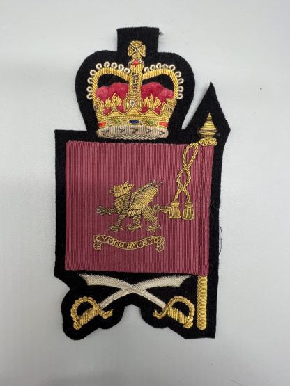 Welsh Guards Company Sergeant Major Rank Insignia, the badge depicts a crimson ceremonial flag with the Welsh Dragon in the centre with the inscription in a scroll Cymru-Am-Byth, surmounted by queens crown