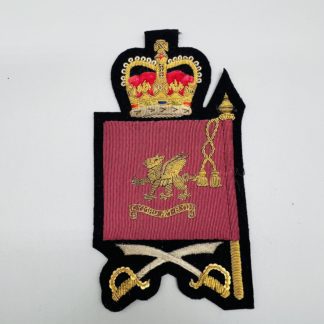 Welsh Guards Company Sergeant Major Rank Insignia, the badge depicts a crimson ceremonial flag with the Welsh Dragon in the centre with the inscription in a scroll Cymru-Am-Byth, surmounted by queens crown