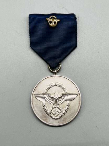 A WW2 German Police Long Service Medal 8 Years, constructed in silvered tombac with period blue ribbon with police motif in the centre.
