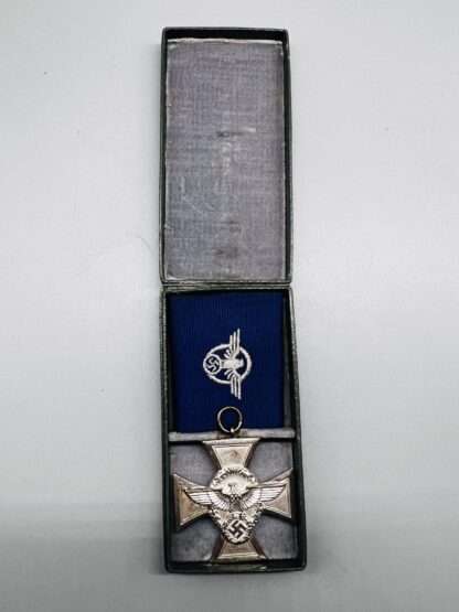 A WW2 German Police Long Service Medal 18 Years, constructed in silvered tombac with a period blue ribbon embroidered with police insignia, placed within presentation case lined in grey felt.