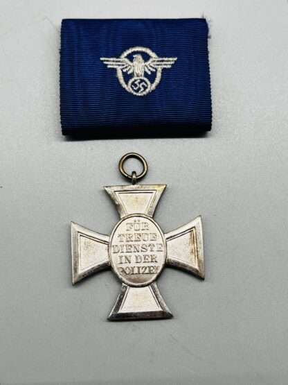 A reverse image of WW2 German Police Long Service Medal 18 Years, constructed in silvered tombac with a period blue ribbon embroidered with police insignia.