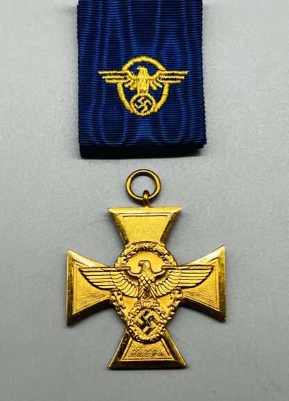 A WW2 German Police Long Service Medal 25 Years, with period ribbon embroidered with insignia. The medal is constructed in tombac with gilt finish with the Police eagle in the centre.