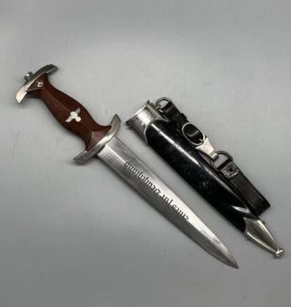 A WW2 German NSKK Dagger By Carl Eickhorn RZM M7/66 1939, with black scabbard, leather hangers, and the blade is inscribed "Alles für Deutschland" (Everything for Germany).