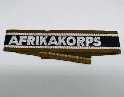 A WW2 German Army AfricaKorp cuff title, machine embroidered with silver aluminum wire, with the inscription “AFRIKAKORP” measuring 34mm (W) x 445mm (L).