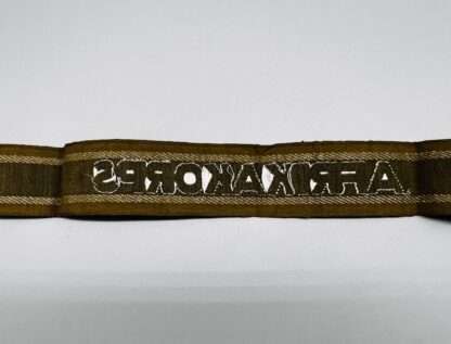 Reverse photo of a WW2 German Army AfricaKorp cuff title, machine embroidered with silver aluminum wire, with the inscription “AFRIKAKORP” measuring 34mm (W) x 445mm (L).