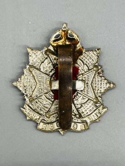 A reverse picture of a WW2 Border Regiment Cap Badge, constructed in white metal with brass slider.
