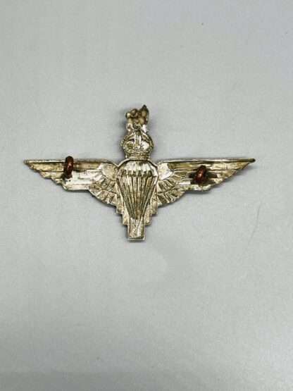 A reverse image of a British WW2 Parachute Regiment Cap Badge, with brass lugs.