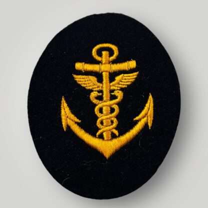 A Kriegsmarine Medical Petty Officer trade badge, machine embroided in golden yellow thread on dark blue wool, oval shapped.