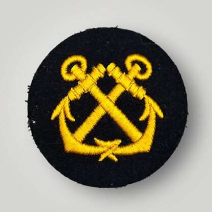 A WW2 Kriegsmarine EM Helmsman sleeve badge, machine embroidered with golden yellow thread on dark blue wool.