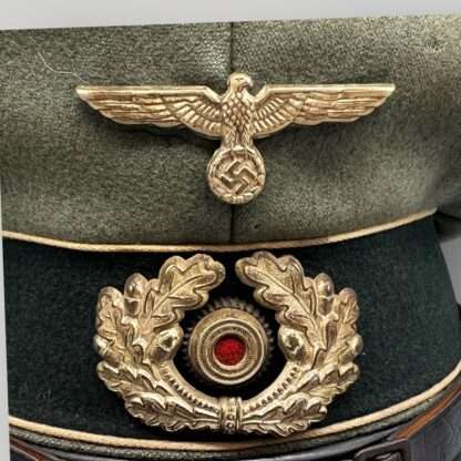 A WW2 German Heer infantry EM/NCO's visor cap, with green central band with wihite pipping, with cupal insignia.
