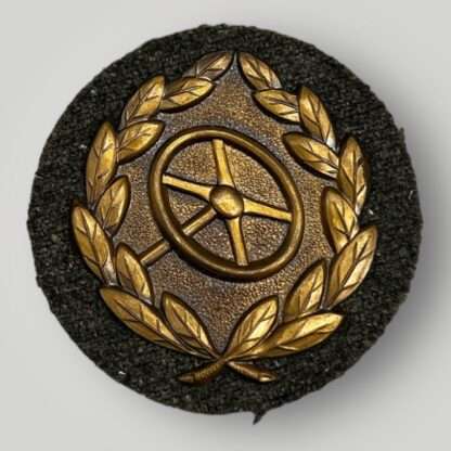 A WW2 driver's proficiency badge in bronze, die stamped construction with green wool backing.
