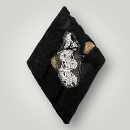Reverse image of an SS medical services sleeve badge, costructed in silver bullion covered in black felt, with buckrum backing.