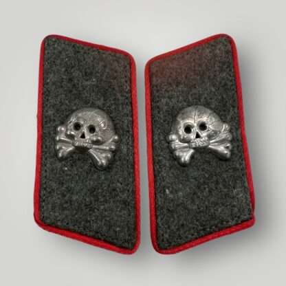 A WW2 German Heer Panzer Stug collar tabs, with alluminium skulls and green woolen backing with red pipping.
