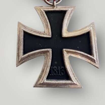 Reverse image of an Iron Cross 2nd Class Medal unmarked, with red, white, and black ribbon.