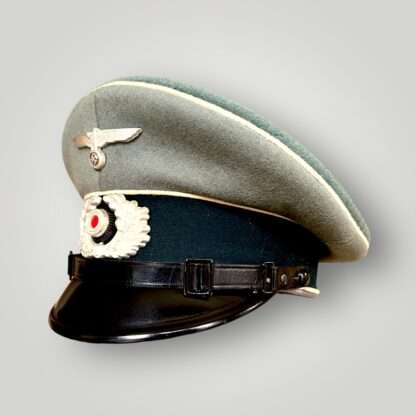 A side view of a WW2 German Heer EM/NCOs Infantry visor cap, with white pipping and green band.