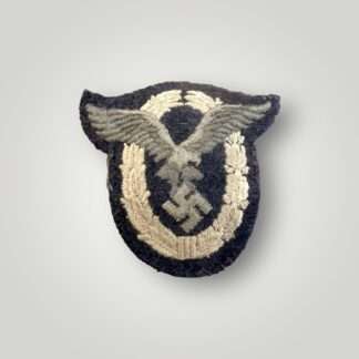 A Luftwaffe Pilots badge in cloth, machine embroidered in grey and silver thread on a dark grey woollen backing.