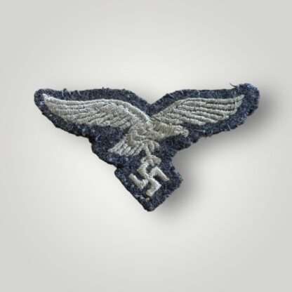 A Luftwaffe M43 cap eagle, machine embroidered in white thread on blue wool backing.