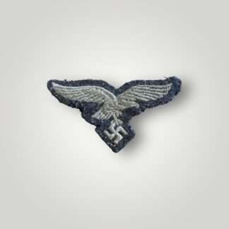A Luftwaffe M43 cap eagle, machine embroidered in white thread on blue wool backing.