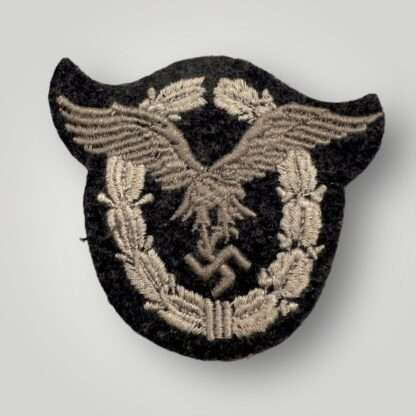 A Luftwaffe Pilots Cloth Badge, machine embroidered in grey and silver on a dark grey wool backing.