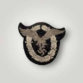 A Luftwaffe Pilots Cloth Badge, machine embroidered in grey and silver on a dark grey wool backing.