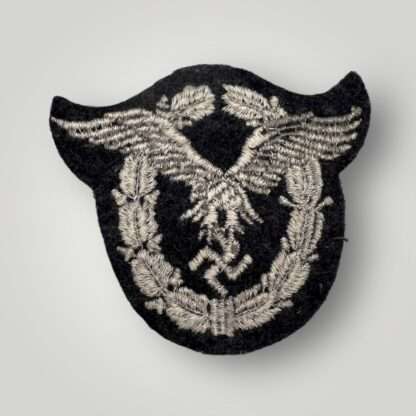 Reverse image of a Luftwaffe Pilots Cloth Badge, machine embroidered in grey and silver on a dark grey wool backing.