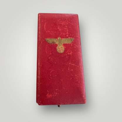 A WW2 German Anschluss medal with presentation case, covered in red leatherette embosed with an eagle and swastika.