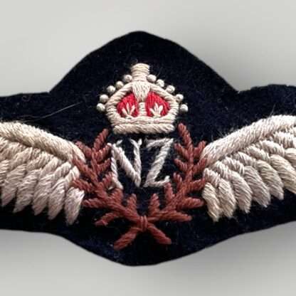 Close up image of a genuine Royal New Zealand WW2 pilot wings, embroidered pair of outstretched wings supporting a central laurel wreath with the 'NF' monogram in the centre for New Zealand surmounted by King's crown.