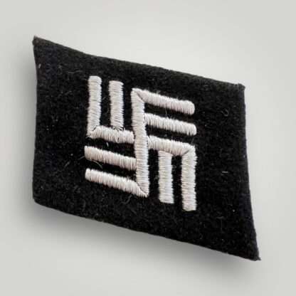 A texbook example of a Waffen-SS Camp Guard collar tab, machine embroidered in white thread on black woollen backing.