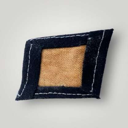 A reverse image of a Waffen-SS Camp Guard collar tab, machine embroidered in white thread on black woollen backing.