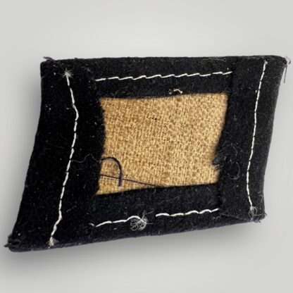 Reverse image of a Waffen-SS 29th Grenadier Division (Russian Volunteers) collar tab, machine embroidered in white thread on black woollen backing.