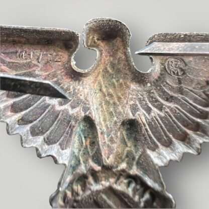 A reverse image of a Waffern-SS Visor cap eagle marked M/72 for Fritz Zimmermann, complete with prongs.