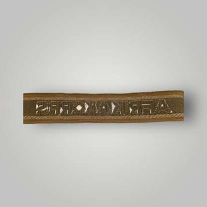 Reverse image of a German Heer AfricaKorp WW2 Cuff Title, machine embroidered with silver aluminum wire, with the inscription AFRIKAKORP.