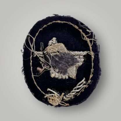 Reverse image of Werkschutz Factory Guard Officers sleeve badge, oval shaped badge hand embroirered in silver bullion wire on black felt backing.