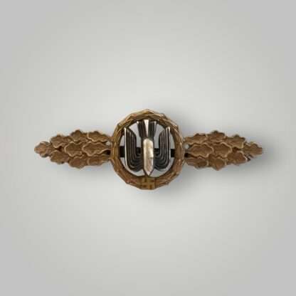 An early Luftwaffe bombers clasp in bronze by Juncker, in gilded tombac. The clasp despicts a vertical diving bomb with wings surrounded by a oak wreath with a swastika at the base, with nine outstretched oak leaves left and right.