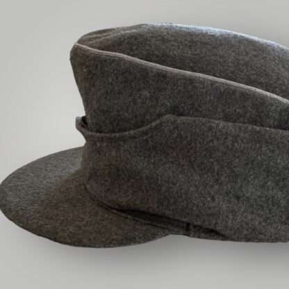 A side view of an orginal WW2 German Heer M43 Officers field cap, constructed in grey field grey wool with aluminium wire piping running around the top of the outer edge of the crown.