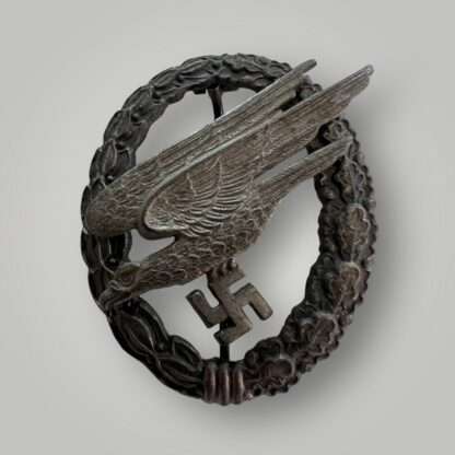 Original late war Luftwaffe Fallschirmjäger Badge by Assmann constructed in zinc. The obverse depicts an oval laurel and oak leaf wreath, with a diving eagle clutching a swastika.