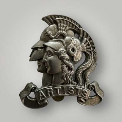 An Artistes Rifles cap badge, constructed in white metal. The badge depicts the classical helmeted heads of Mars and Minerva, looking left, resting on a title scroll marked ‘ARTISTS’.  The reverse comes complete with brass slidder.