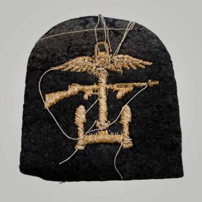 Reverse image of an British WW2 Royal Navy Combined Operations Badge, tombstone shaped badge machine embroiderd in yellow thread on dark blue woollen backing.
