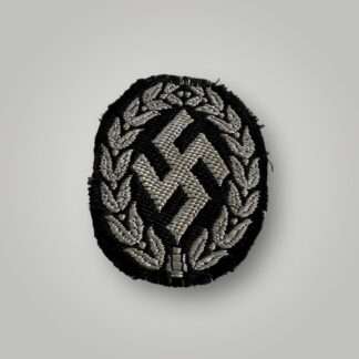An original Schutzmannschaft Bevo cap badge, flat wire constructionin in silver wire on black rayon backing.