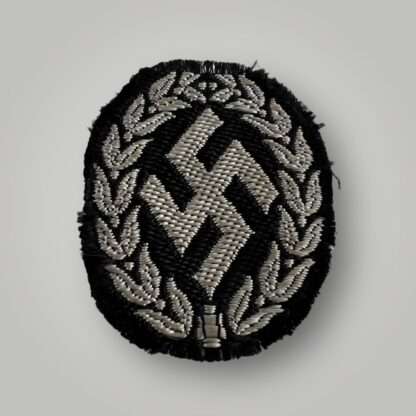 An original Schutzmannschaft Bevo cap badge, flat wire constructionin in silver wire on black rayon backing.