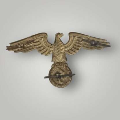 Reverse image of an Reich Ministry of Eastern Territories visor cap insignia, die stamp construction in aluminium with gilt finish.