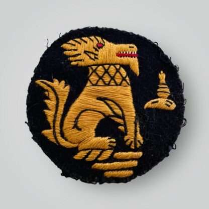 An original Chindit formation badge, machine embroiderd in gold, red, and black thread on blue woollen backing.