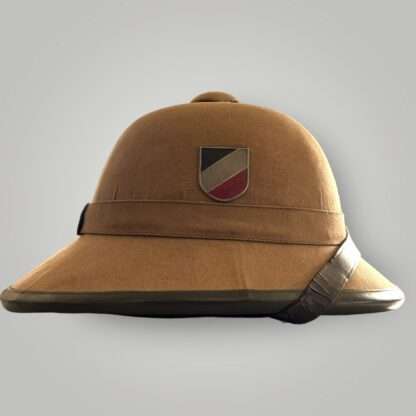 A Heer captured tropical pith helmet, constructed in cork covered in khaki coloured cotton, with dark brown leather chip strap and alloy National tri-color shield.