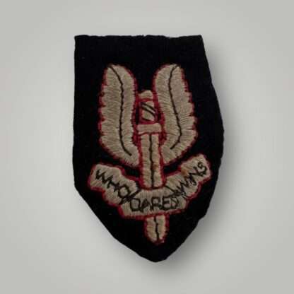 An original British Special Air Service cap insignia circa 1980’s, machine embroidered on black woollen backing