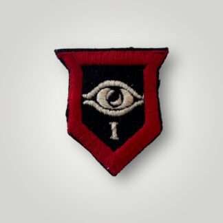 A British WW2 1st Armoured Guards Division formation badge, machine embroidered in dark blue shield with red outer border within which an eye motif above the figure I