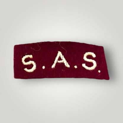 A British Special Air Service WW2 shoulder title, machine embroidered in Cambridge blue thread on maroon woollen backiing.