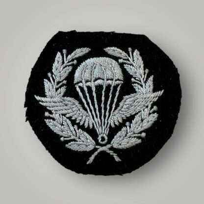 A rare original British Parachute Jump Instructor (PJI) Qualification Badge, machine embroidered in pale blue thread on black wollen backing.