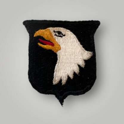 An original US WW2 101st Airborne Division cloth badge type 3 variant, machine embroidered in yellow, red, and white thread on black backing.