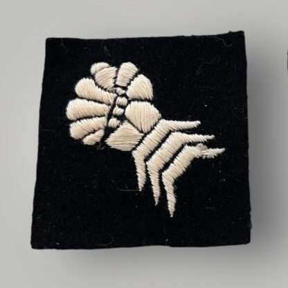 A orginal British WW2 6th Armoured Division formation badge, machine embroidered depicting a clenched mailed gauntlet in white on a black woollen square.