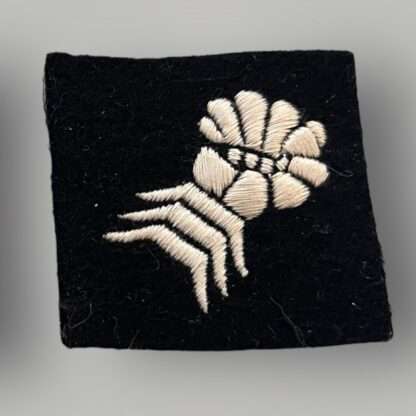 A orginal British WW2 6th Armoured Division formation badge, machine embroidered depicting a clenched mailed gauntlet in white on a black woollen square.